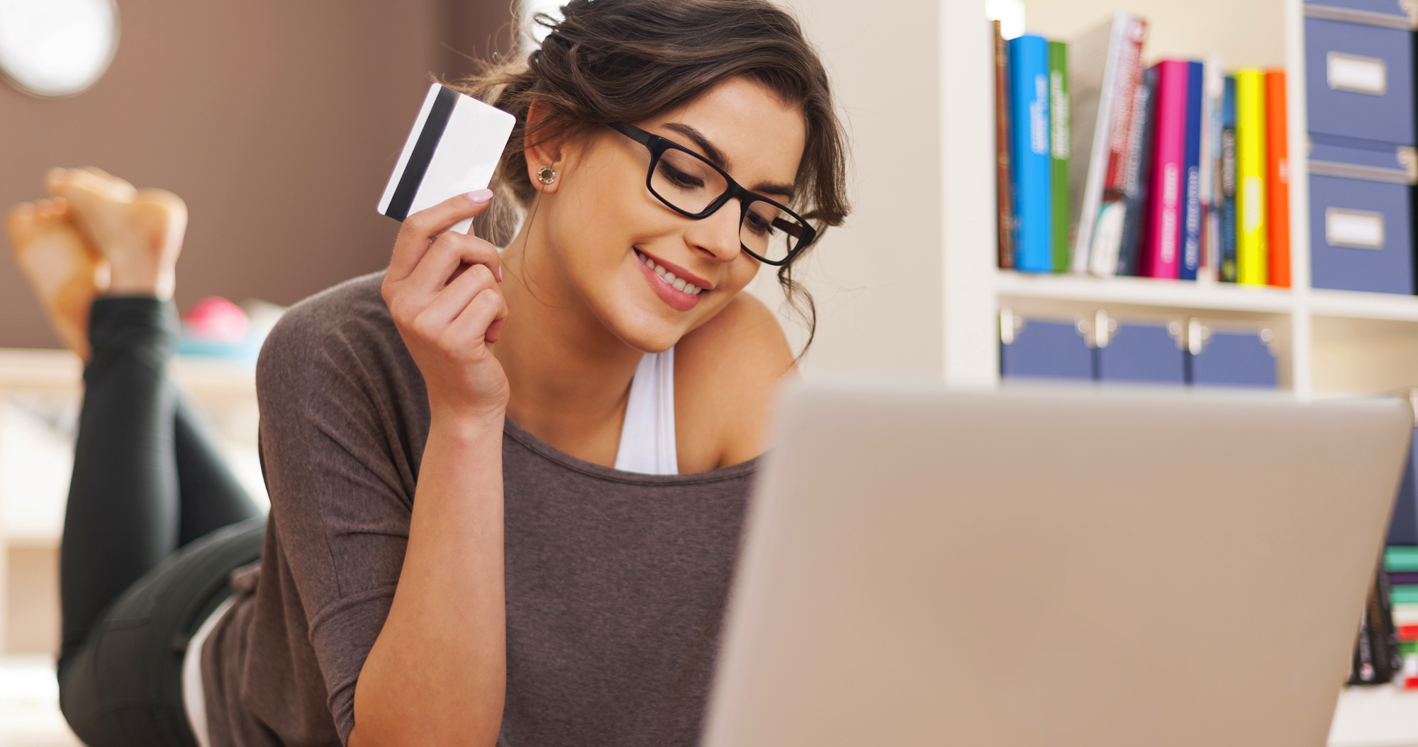 Smiling woman holding a credit card while looking at a laptop for a Galactic corporate merchandise program video production. 
